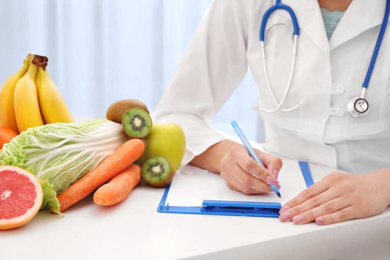 Nutritionist doctor writing diet plan on table
