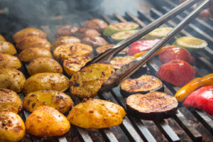 Fresh vegetables roast on a large grill