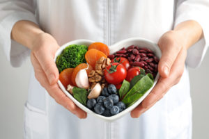Doctor holding bowl with products for heart healthy diet, closeup