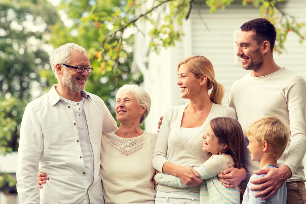 family, happiness, generation, home and people concept happy family standing in front of house outdoors