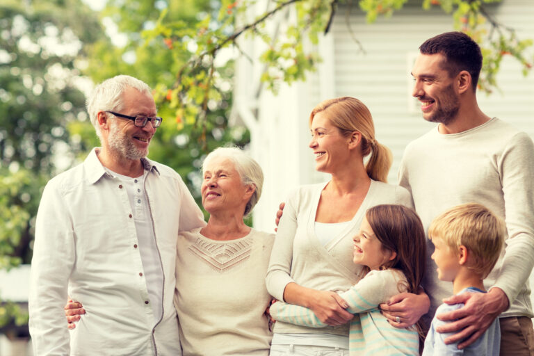 family, happiness, generation, home and people concept happy family standing in front of house outdoors
