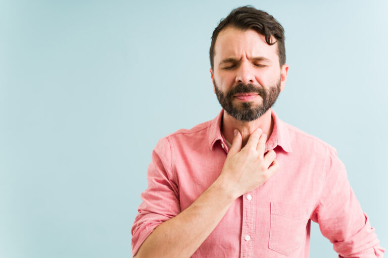 Worried man in his 30s with a sore and irritated throat. Latin man suffering from an infection because of a virus