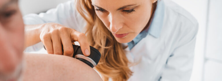 Doctor dermatologist examines skin of patient. Dermatoscopy, prevention of melanoma, skin cancer.