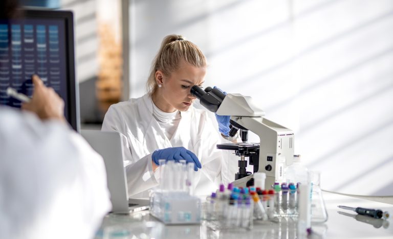 Clinical researcher looking into a microscope in a laboratory.